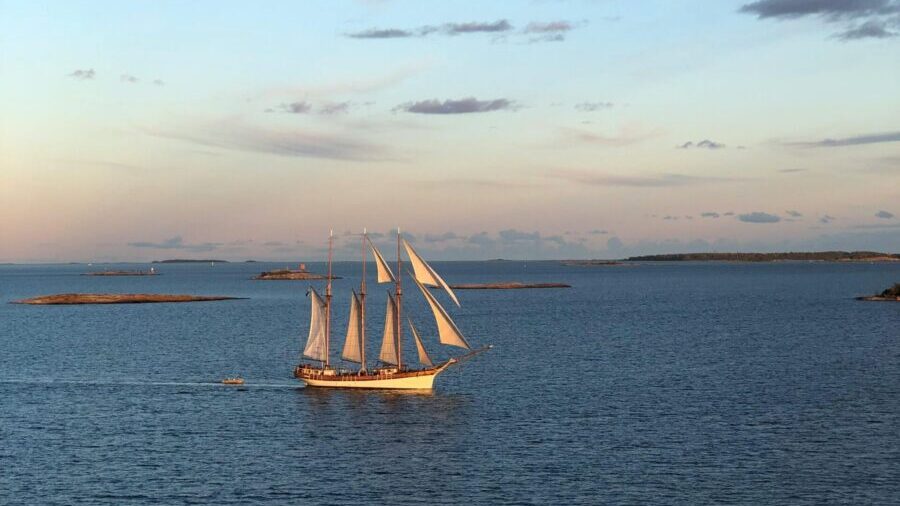 A majestic sailboat glides on the open sea during a picturesque sunset.